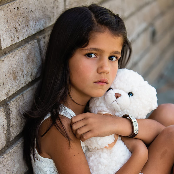 girl wearing safe band holding teddy bear